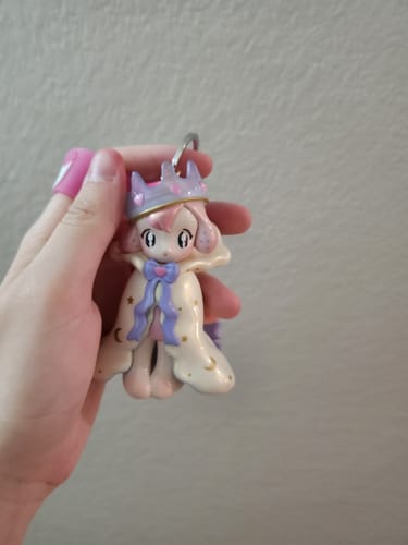 Customer holding an adorable KikaGoods Handmade Keychain showing a girl figure with a crown and a starry cloak.