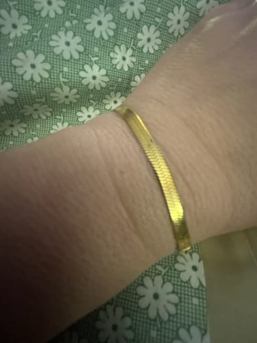 Close-up of a customer wearing the gold herringbone Essentials Bracelet on their wrist.