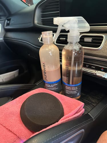 Customer's round black Foam Applicator on a pink cloth next to cleaning products inside a car.