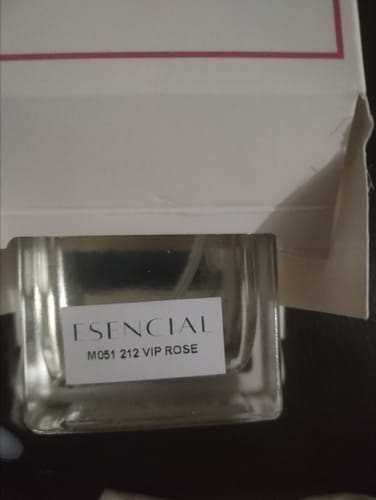 Cliente mostrando un primer plano del frasco de perfume Esencial M051 212 VIP Rose delante de su caja.