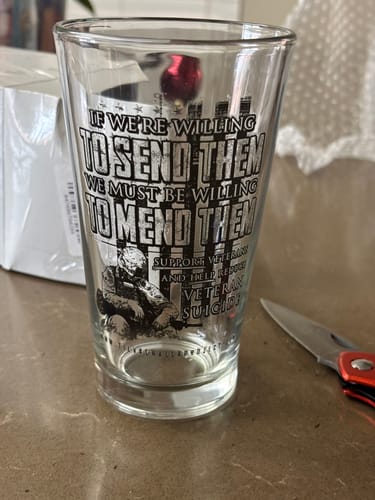 Reviewer's 'We Must Mend Them' glassware, showing the printed design with a soldier and a veteran support message.