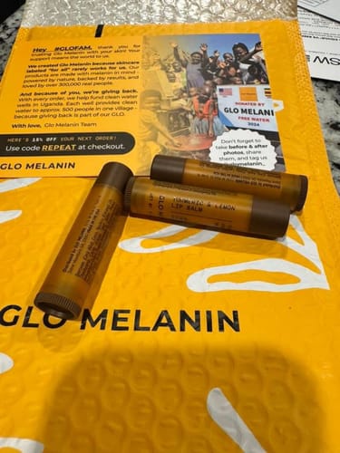 Reviewer's three lip balms from the Brightening Lip Bundle on their yellow packaging.