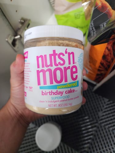 Customer holding a jar of the Birthday Cake PB Powder, showing the front label.