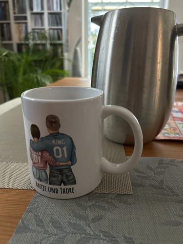 Kundenfoto einer personalisierten Tasse mit einem Paar-Motiv, den Nummern 01 und den Namen „Antje und Thore“.