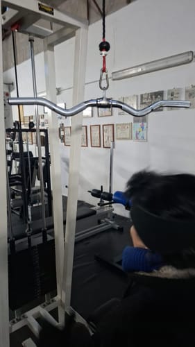 Rezensent im Fitnessstudio mit dem an einer Kabelzugmaschine befestigten SZ-Griff.