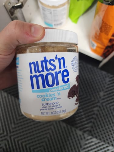 Reviewer holding a jar of Nuts 'n More Cookies 'n Cream PB Powder.