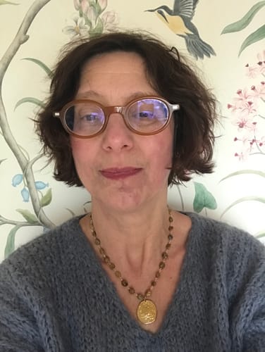 Une cliente portant le collier Mélodie olivine avec un pull en maille gris.