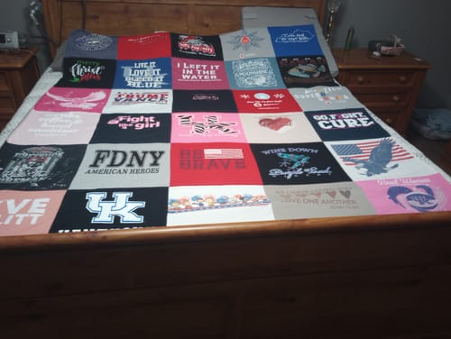 Customer's colorful Premium T Shirt Quilt, made from many different t-shirts, spread across a bed.