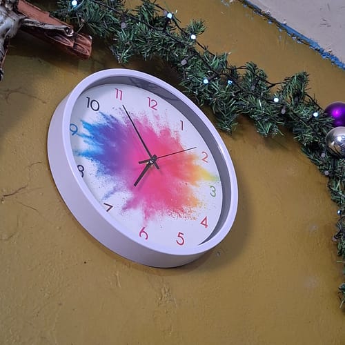 Cliente muestra su Reloj de pared Bloom Colors con diseño colorido, colgado en la pared.