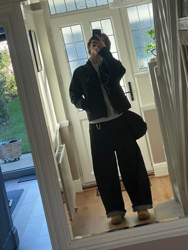 Reviewer in a mirror selfie wearing black Raw Baggy Denim Jeans, cuffed at the ankles in a hallway.