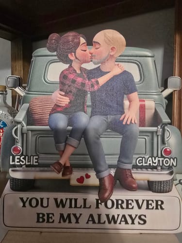 Customer's personalized wooden plaque showing a couple kissing on a truck, customized with the names Leslie and Clayton.