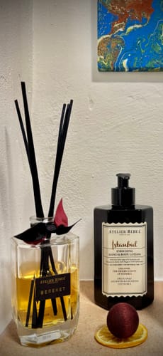 Recensent's Istanbul Hand & Bodylotion in een zwarte fles, uitgestald naast een geurverspreider.