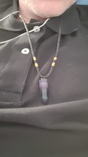Customer wearing the Natural Fluorite Necklace with a dark purple crystal against a black shirt.