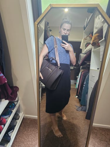 Reviewer in a mirror selfie wearing the Logo Bag Strap on a dark brown bag.