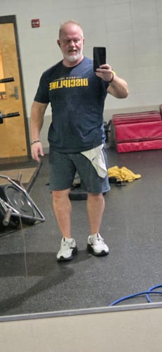Reviewer taking a mirror selfie in a gym, wearing the dark 'Do the Work' t-shirt.