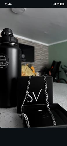 Un cliente muestra la Cadena Fígaro 5mm sobre su elegante caja de empaque negra.