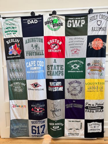 Customer's large Premium T Shirt Quilt hanging on display, showing a colorful patchwork of memorable t-shirts.