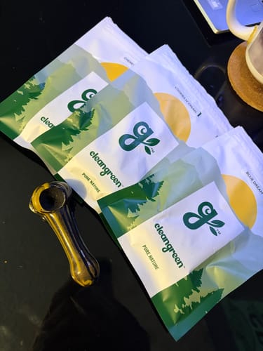 Customer's array of cleangreen products, including Cookies N’ Cream, fanned out next to a glass pipe.