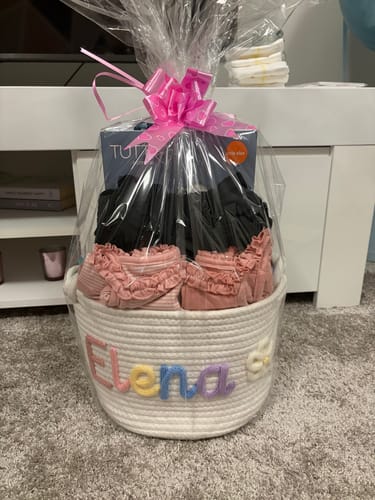 Customer's white personalized knitted basket with 'Elena' in multicolor letters, used as a baby shower gift hamper.