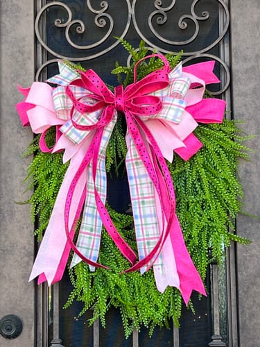 Customer's hot pink and black polka dot ribbon styled in a large, multi-ribbon bow on a green wreath.