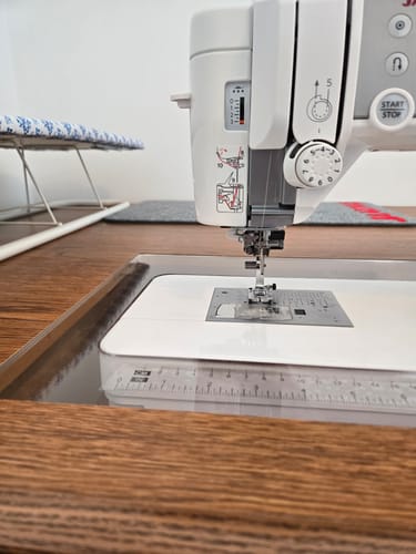 A customer's Sew Steady Custom Acrylic Cabinet Insert creating a flush, smooth surface around a white sewing machine in a wooden cabinet.