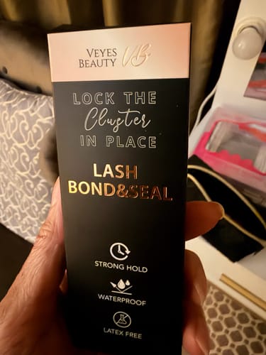 Customer holding the black packaging for the Lash Bond & Seal used to apply LuxeBold lashes.