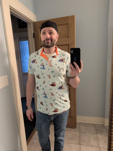 Customer wearing The Flintstones 'Loyal Order of Dinosaurs' Tourney' polo shirt with blue jeans in a room.