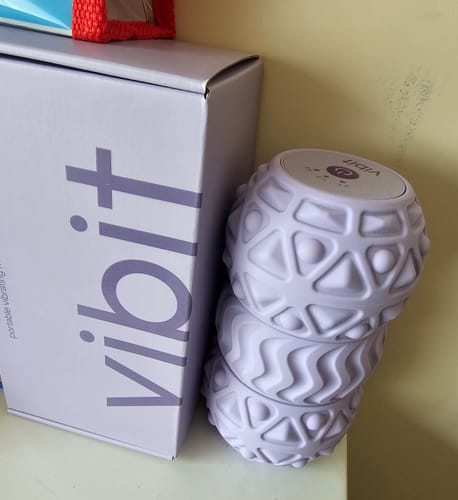 Customer's three purple Vibit ROLL massage rollers stacked next to their product box.