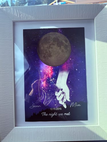 Customer's personalized Galaxy Night poster in a white frame, showing holding hands, a moon, and custom text.