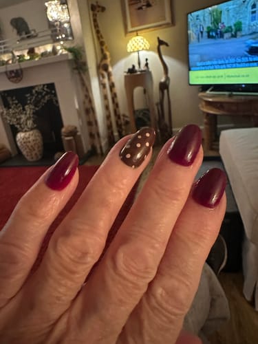Reviewer's hand showing a mixed manicure with the Spot On press-on nail, featuring a brown polka dot design.