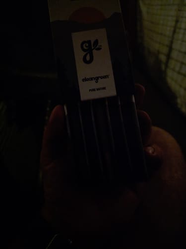 Reviewer's hand holding the packaging for Cherry Dosi-Do Pre-Rolls in a dark setting.