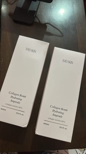 Customer's two white boxes of Bad Skin Collagen Bomb Hydrating Ampoule on a wooden surface.