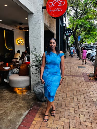 Customer poses on a sidewalk in the blue Abstract Mesh Off Shoulder Midi Dress.