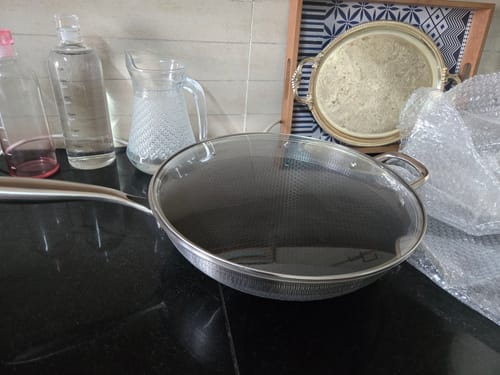Customer's new laser crafted honeycomb pan with a glass lid, pictured on a black countertop.