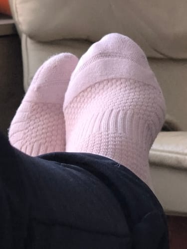 Nærbillede af en anmelders fødder iført lyserøde Støttestrømper, mens de slapper af.