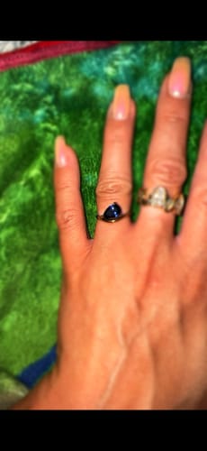 Customer's hand wearing the Pia Birthstone Ring with a dark pear-shaped stone on their finger.