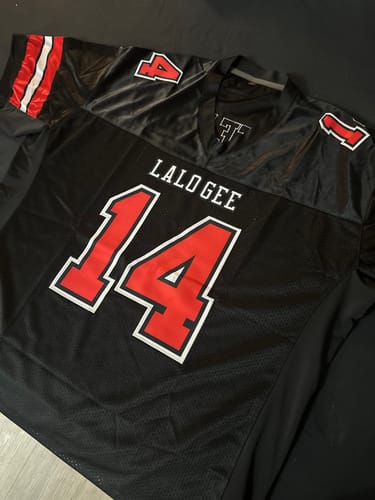 A customer's custom black football jersey laid flat, showing the name 'LALOGEE' and number '14' in red and white.