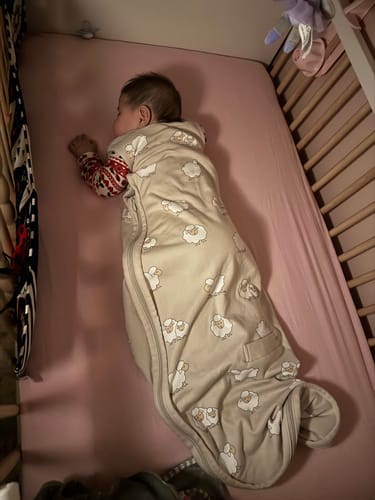 Customer's baby sleeping in a crib wearing the sheep-patterned 4 Season® Ultimate Baby Sleep Bag.