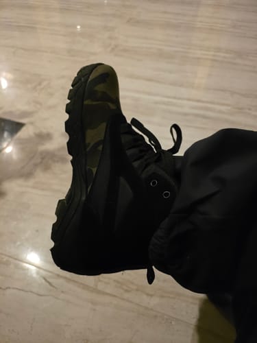 Reviewer wearing a black Bacca Bucci Hunter 2.0 ankle boot with a camouflage pattern on the heel.