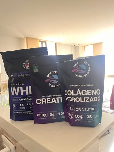 Reseñador muestra la Proteína Whey de Chocolate junto a otros productos de la marca en un mostrador.