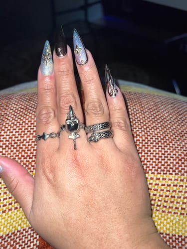 A customer's hand wearing the Upgraded Slime Ring on their middle finger, styled with other rings and elaborate nails.