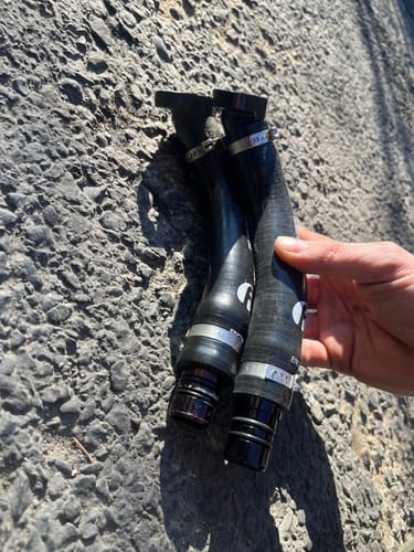 Customer holding the new Cummins Turbo Drain Tube Kit next to the old part for a side-by-side comparison.