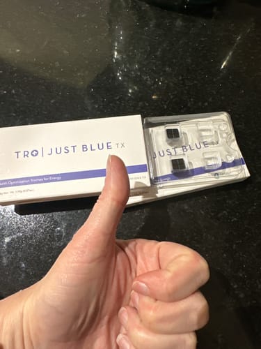 Reviewer gives a thumbs-up with the Just Blue box and a blister pack of troches on a counter.