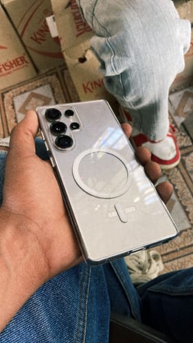 Reviewer holds a Samsung Galaxy S25 Ultra in the clear Magsafe case, showing the prominent magnetic ring.