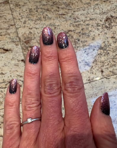 Kundin zeigt ihre Hand mit den glitzernden 'Dreamy Rosé' Nagelfolien, die einen schwarz-roséfarbenen Ombré-Verlauf haben.