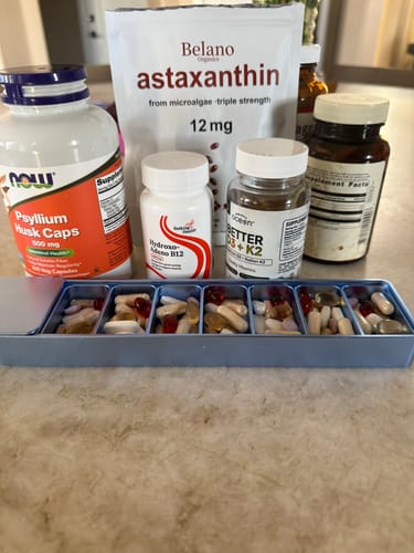 Customer's open blue Weekly Case filled with supplements, sitting in front of several large vitamin bottles.