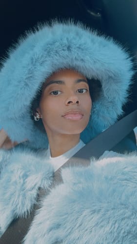 Close-up of a reviewer wearing the matching plush, light blue faux fur hat and top mentioned in their review.