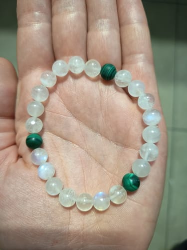 Cliente montrant le Bracelet Grossesse avec ses perles de pierre de lune et de malachite, tenu dans sa main.