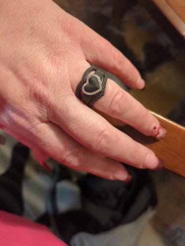 Customer's hand wearing the black silicone heart ring with a shiny CZ stone frame.