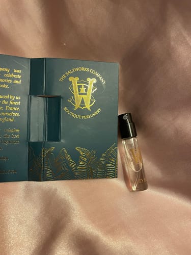 Customer's sample vial of Honeyberry perfume next to its dark green and gold packaging.